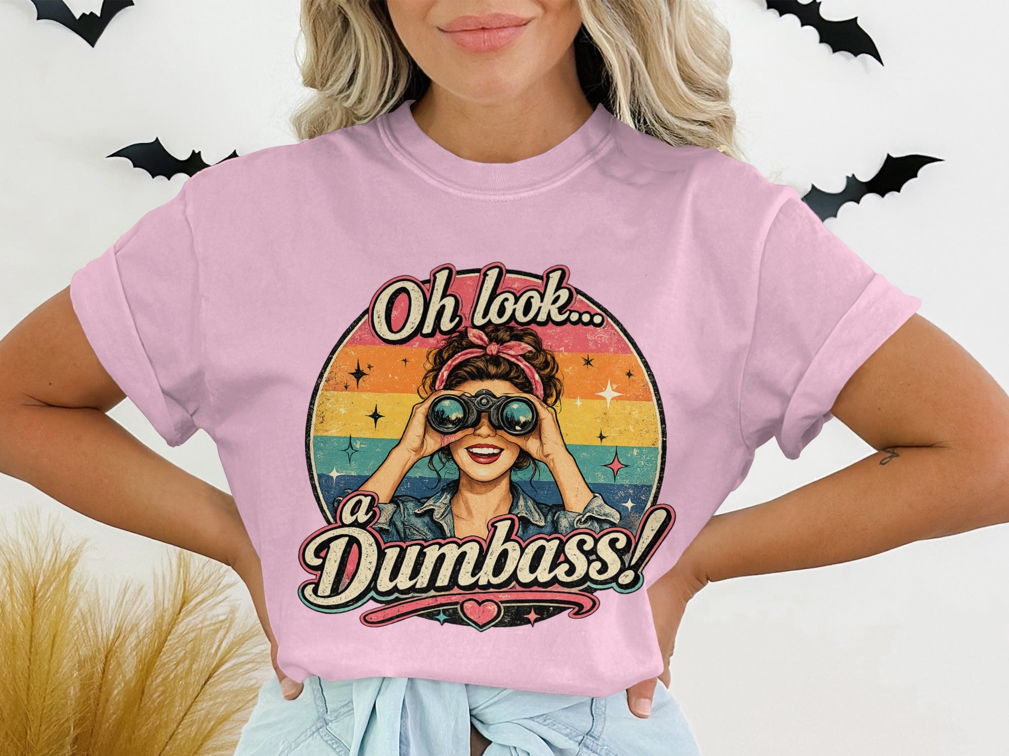 Pink t-shirt with "Oh look... a Dumbass!" graphic and retro woman using binoculars.