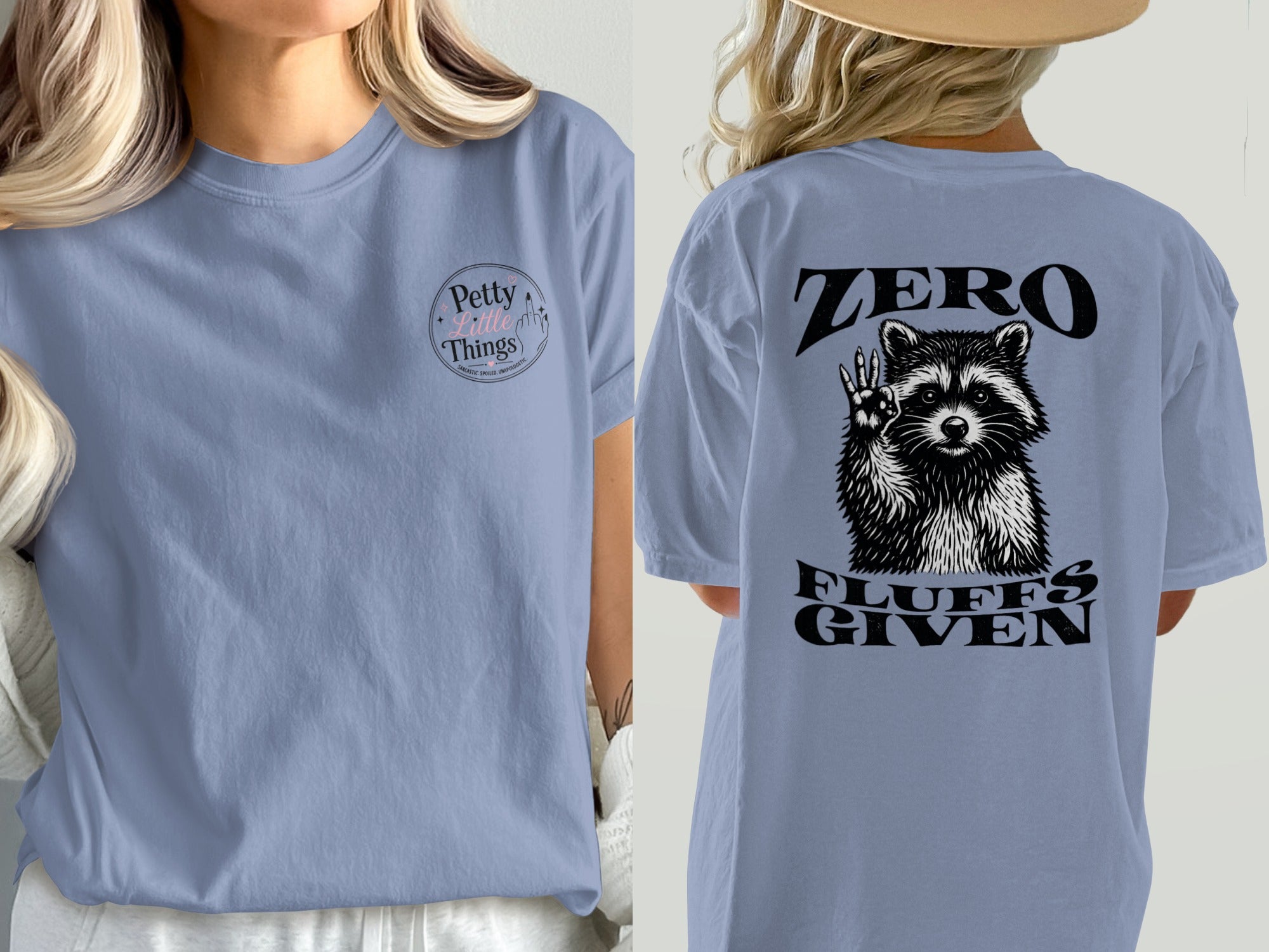 Blue t-shirt with "Petty Little Things" logo on the left chest and raccoon graphic with "Zero Fluffs Given" on the back.