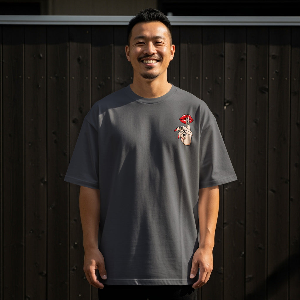 Man in charcoal t-shirt with "Shut The Fuck Up" graphic on left chest.