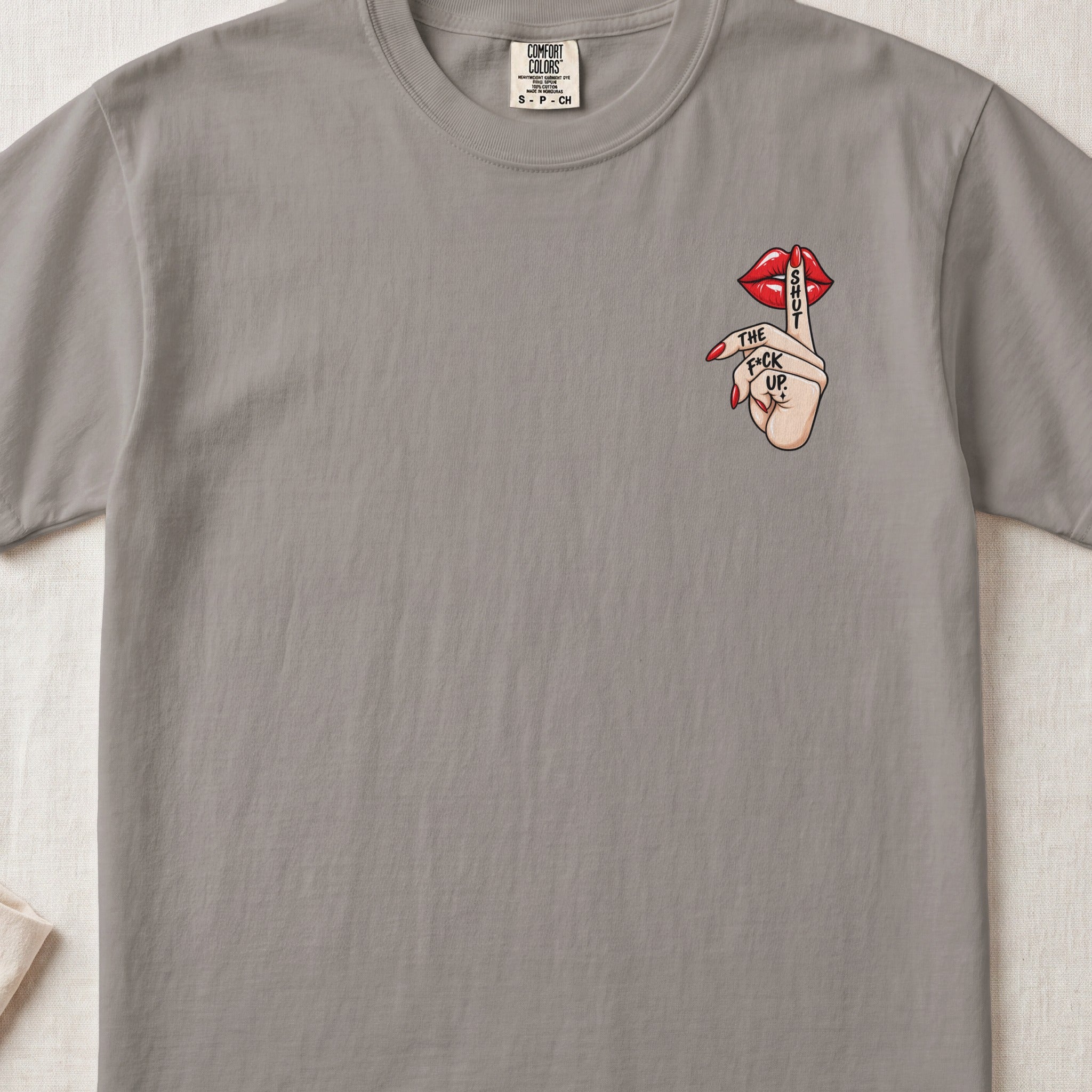 T-shirt with a graphic of red lips, a finger to the lips, and "SHUT THE F*CK UP." text.