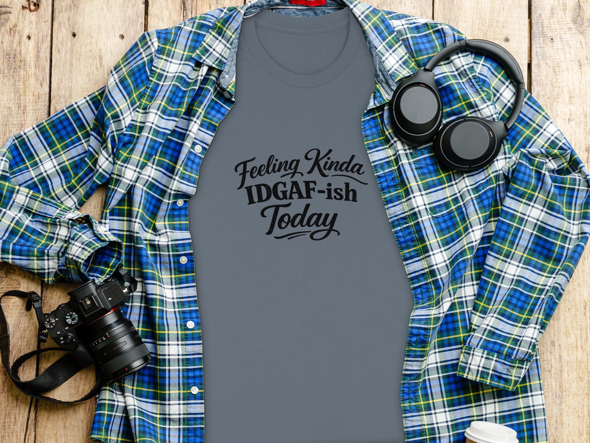 Grey t-shirt with "Feeling Kinda IDGAF-ish Today" text, open plaid shirt, headphones, and camera.