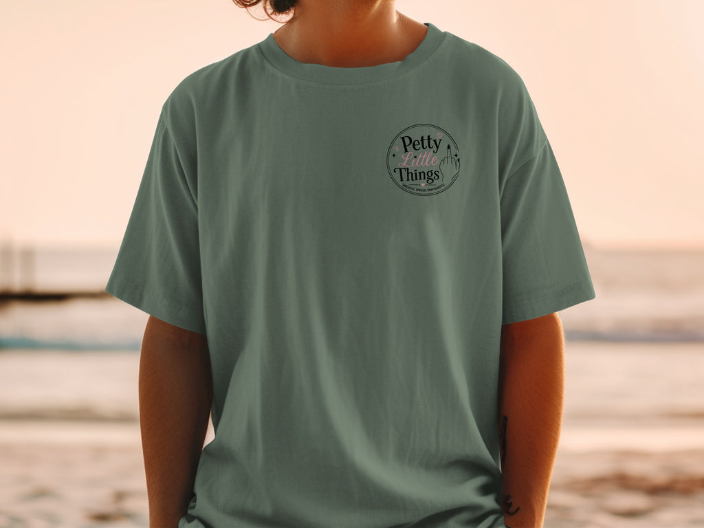 Green t-shirt with a circular graphic containing text "Petty Little Things" and a middle finger.