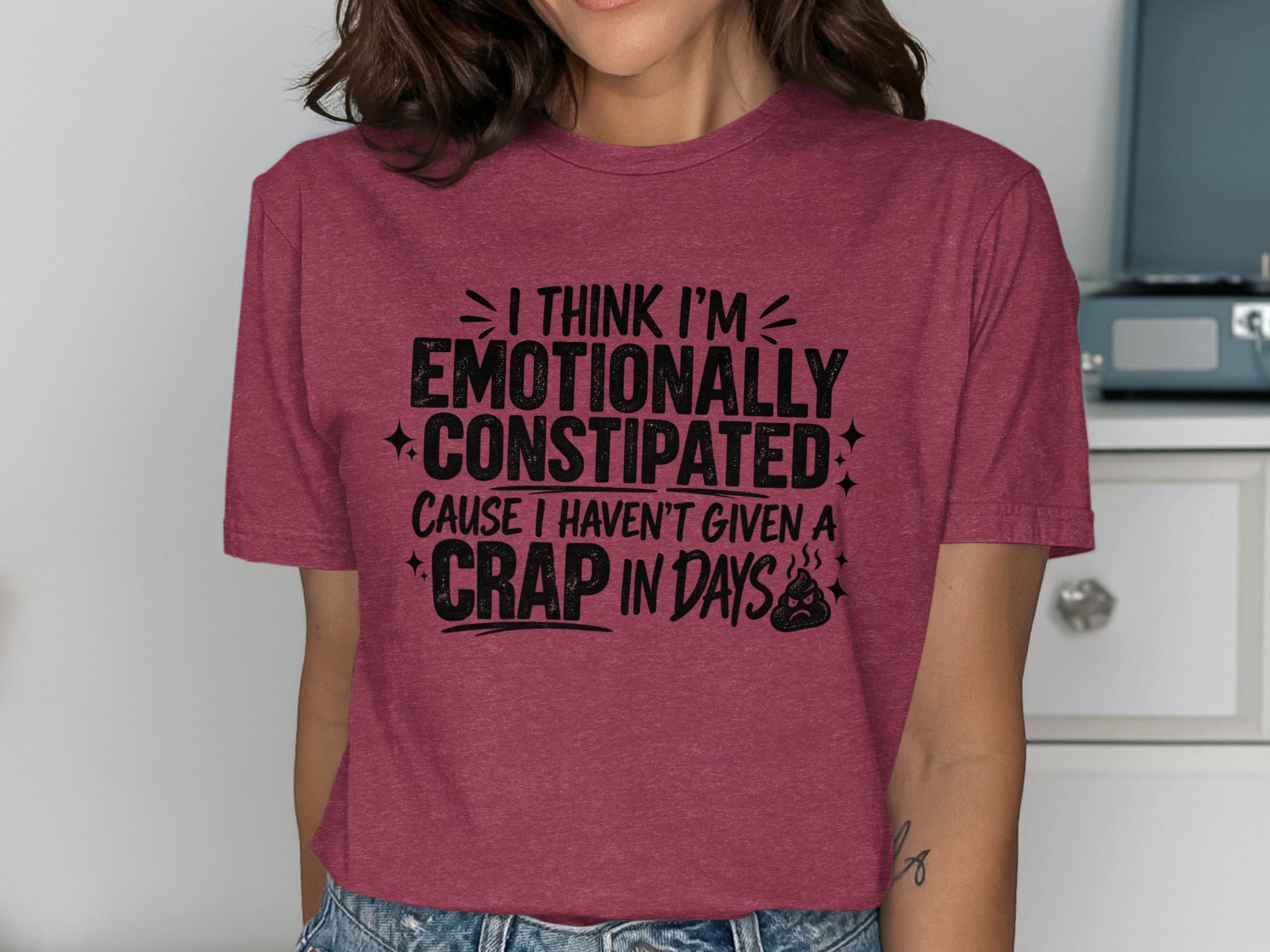 Maroon t-shirt with black text reading "I THINK I'M EMOTIONALLY CONSTIPATED CAUSE I HAVEN'T GIVEN A CRAP IN DAYS" and a poop emoji.